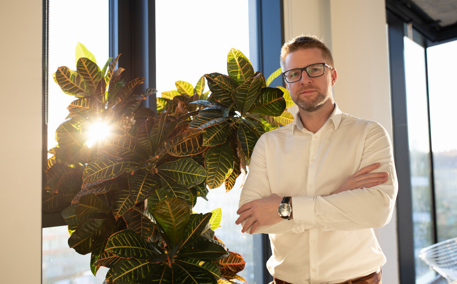Man standing by a window, symbolizing strategic planning for Danish-Czech business deals.