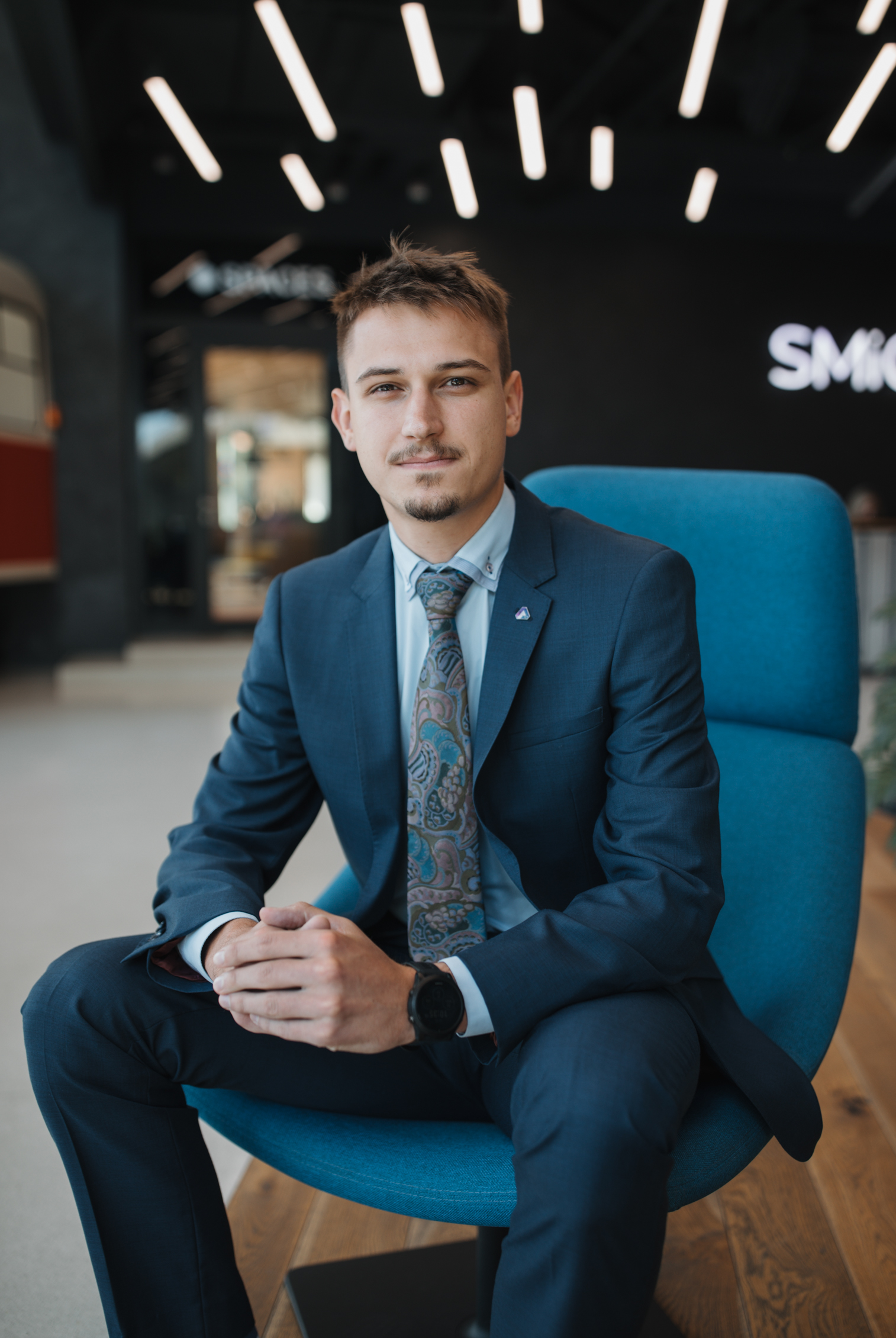 Muž v obleku sedí v moderní kanceláři, připravený k profesionálnímu jednání.