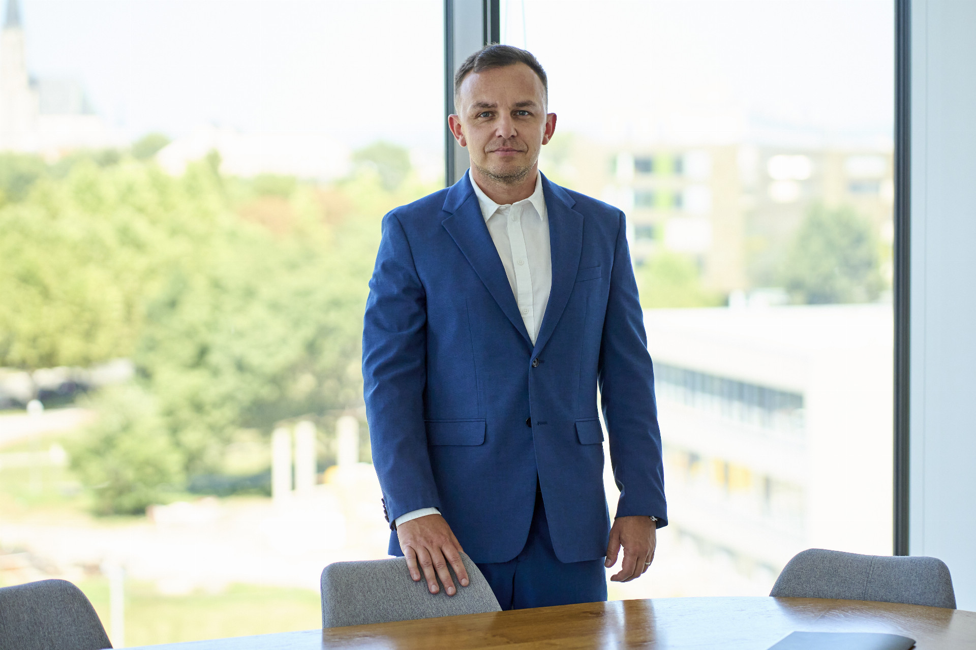 Man in a blue suit stands in an office, related to environmental inspection in manufacturing.