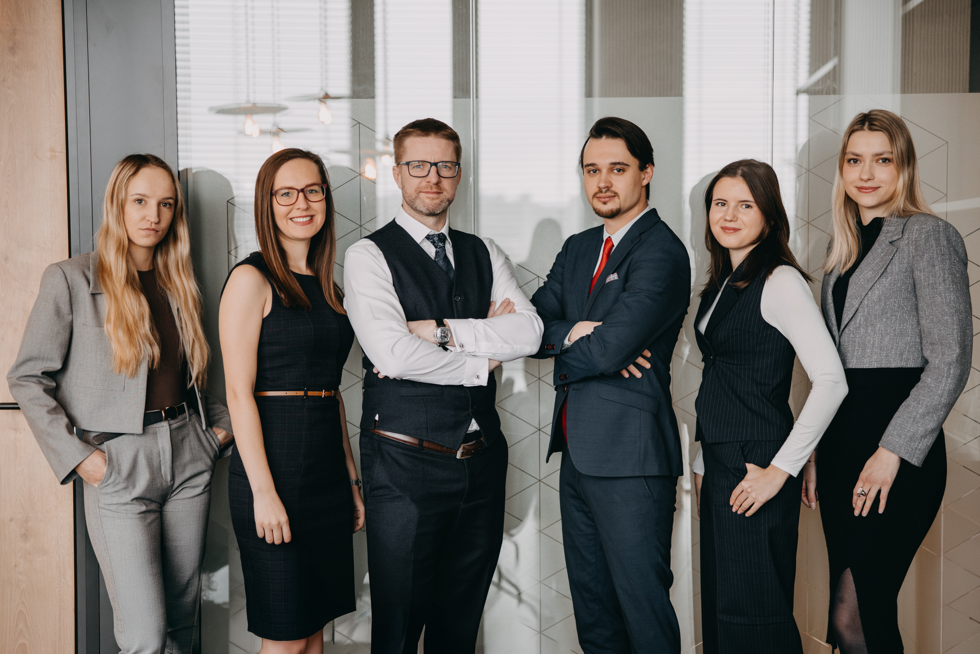 A team of six professionals in an office setting, dressed in elegant formal attire.