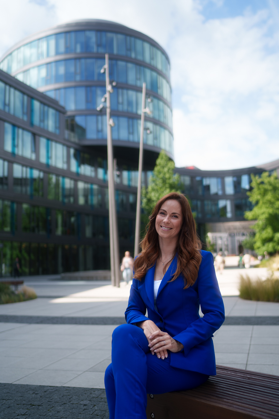 A woman in a blue suit is sitting in front of a modern office building.